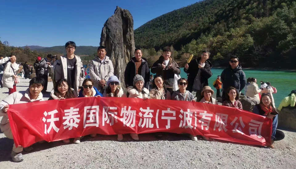 Outdoor group holding a red banner displaying the company's Chinese name.