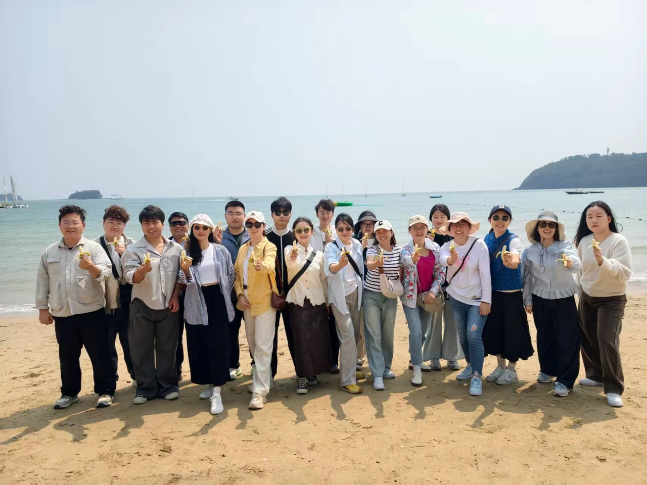 Group photo by the sea, with participants holding bananas.